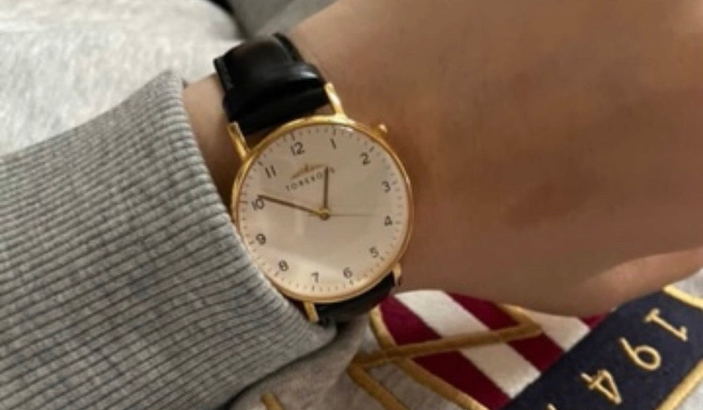 Barnklocka guld med svart skinn på pojkes handled.