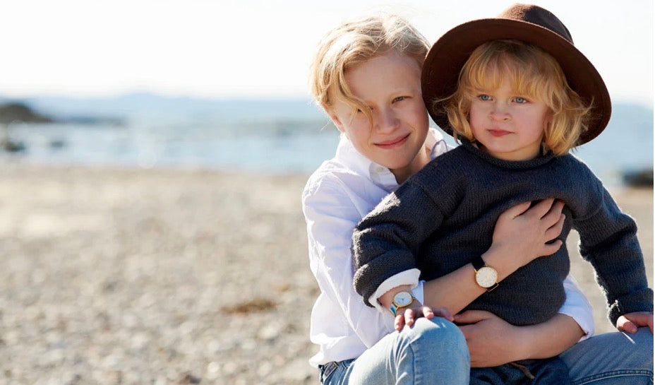 Analoga barnklockor i guld på liten pojke med storebror